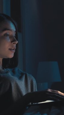 İnternetteki konferans. Uykusuz kadın. Sanal yaşam. Aydınlık gölge odasının içinde dizüstü bilgisayarla konuşan oldukça yorgun bir kadın. Dikey video.