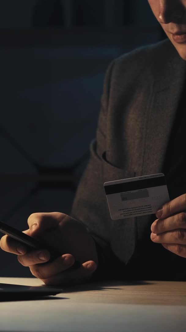 银行骗局 移动钓鱼 网上交易风险 无法辨认的商人在工作场所深夜使用信用卡支付互联网费用 垂直录像 — 图库视频影像