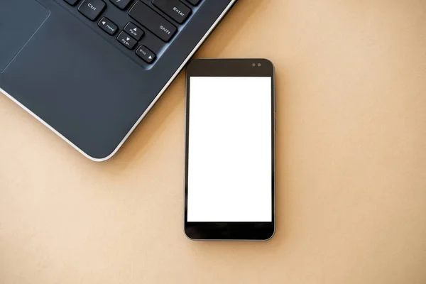 Mobile mockup. Online technology. Virtual life. Smartphone with white blank screen and opened laptop on beige table.