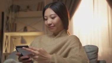 Banka uygulaması. Elektronik para transferi. Dijital ödeme emniyeti. Modern ev iç mekanında kredi kartı kullanmaktan memnun bir kadın..