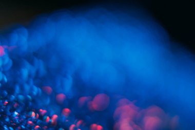 Bokeh meşalesi. Bulanık neon parıltısı. Ultraviyole ışınlar yansıtır. Odaklanmamış lacivert pembe, yuvarlak pullu lekeler koyu siyah fütürist soyut arka planda parlıyor..