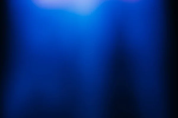 Blur glow overlay. Neon light flare. Futuristic glare. Defocused fluorescent navy blue white color gradient rays reflection on dark abstract copy space background.