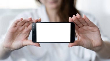 Dijital bir model. Mobil özçekim. Çevrimiçi bağlantı. Işıklandırma odasının iç kısmında elinde boş ekranlı akıllı telefon tutan tanınmayan bir kadın..
