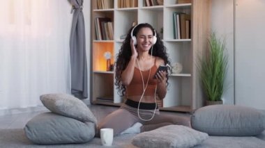 En sevdiğin şarkı. Müzik eğlencesi. Gadget 'ın boş vakti. Çok mutlu bir kadın telefon ile müzik listesi dinliyor evdeki oturma odasında yerde..