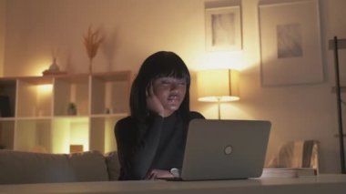 Night study. Online learning. Student insomnia. Tired sleepy woman watching video class using laptop late at dark home workplace interior with free space.