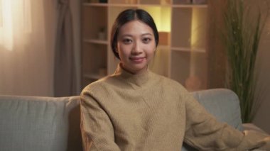 Rahat kadın. Ev istirahatı. Pozitif yaşam tarzı. Kendine güvenen, gülümseyen bir kız, modern oturma odasında, koltukta tek başına oturuyor..