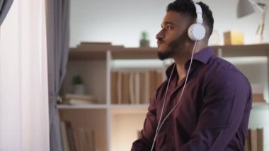 Music energy. Carefree leisure. Modern sound technology. Relaxed inspired man enjoying listening mp3 in headphones dancing drinking tea at home interior with free space.