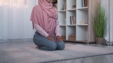 Dindar Müslüman. Allah 'ın inancı İslam dini. Geleneksel tesettürlü tanınmayan bir kadın evde, oturma odasında yerde dua ediyor..