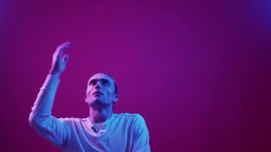 Yüz jesti. Sıkıcı ifade. Hata pişmanlığı. Mavi neon ışığı rahatsız edici yorgun adam pembe mor renk gradyan fotokopi arkaplanı üzerinde izole bir tepki.