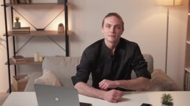 Başarılı insanlarız. Profesyonel kariyer. Liderlik hırsı. Modern ev içi iş yerinde laptopuyla güler yüzlü yakışıklı bir iş adamı..