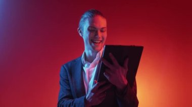 Dijital pazarlama. İş teknolojisi. Bilişim teknolojisi yeniliği. Kırmızı turuncu renk gradyan boş arkaplanda izole edilmiş tablet kullanan neon ışığı meraklısı adam.