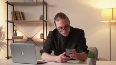 İnternet işi. Evden çalışıyorum. Dijital araştırma. Uzaktan kumanda. Kendine güveni tam, gözlüklü, modern ofis içi iş yerinde dizüstü telefonu kullanan..