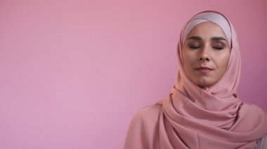 Puzzled woman. Decision making. Offer choice. Problem solution. Pensive thoughtful woman in hijab portrait isolated on pink copy space advertising.