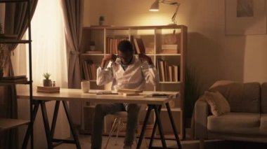 Doktor molası. İşten sonra kestiririm. Profesyonel tükenme yorgunluğu. Yorgun erkek pratisyen iş yerinden çıkarken modern iç mekanda koltukta uyuyakalıyor..