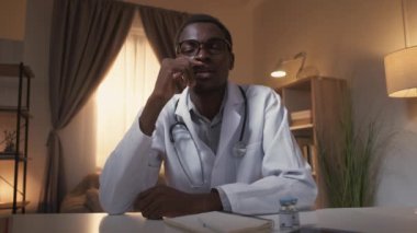 Tıbbi webinar. Tele-sağlık sohbeti. Sanal tanı. Kafası karışmış erkek doktor, tedaviyi evde, modern iç mekanda tartışmayı düşünüyor..