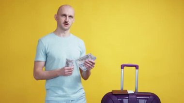 Tatil bütçesi. Maceracı adam. Seyahat planı. Yolculuk için para sayan mutlu hayalperest adam sarı arka planda yabancı pasaportla kalıyor..