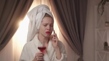 Üzücü bir telefon görüşmesi. Depresyon içeceği. Yalnız hafta sonu. Mobil iletişim. İç mekanında sızlanan kırmızı şaraplı bornoz giymiş üzgün bir kadın..