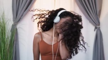 Müzik tatmini. Favori çalma listesi. Ses aygıtı. Neşeli kaygısız kadın kulaklıkla dans ediyor saçlarını savuruyor evde telefonda şarkı söylüyor..