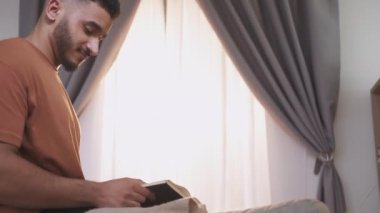 Okuma öğrenme. Ev tatili. Bilgi eğitimi için. Açık kitabı olan rahat zeki bir adam açık pencere arkaplanında boş alanı olan sayfaları çeviriyor.