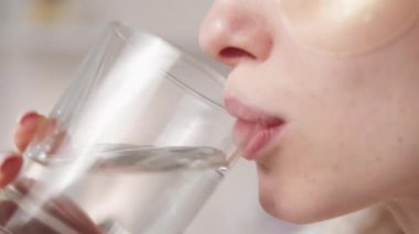 Healthy hydration. Skin detox. Wellbeing beauty care. Closeup profile of unrecognizable woman with clean face hydrogel under eye patches enjoying drinking mineral water.
