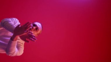 Dikey video. Hadi canım. Reddetme işareti. Olumsuz tepki. Reddedildi. Mor neon ışığı, hoşnutsuz adam kırmızı renkli boş alan arka planında el sallamayı reddediyor..