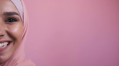 Optimistic woman. Happy portrait. Womens day. Joyful toothy smile half face of laughing lady in hijab isolated on pink empty space studio background.