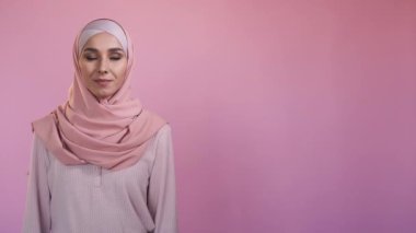 Islamic woman portrait. Positive emotion. Advertising banner. Happy optimistic pretty female in hijab isolated on pink copy space background.