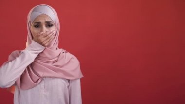 Kadın hakları için. Kadın ayrımcılığı. Cinsiyet eşitliği. Üzüntülü, konuşamayan, tesettürlü, ağzı kapalı, elleri kırmızı, boş bir alanda izole edilmiş bir kadın..