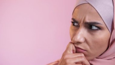 Düşünen kadın. Düşünceli bir ifade. Reklam arkaplanı. Tesettürlü düşünceli bir kadının portresi. Pembe fotokopi alanında karar veriyor..