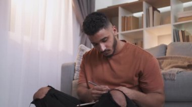 Çizim hobisi. Sanat haftasonu eğlencesi. Yaratıcı ilham. Rahat adam yerde bağdaş kurarak oturuyor. Açık modern iç mekanda çizim yapıyor. Boş alanı var..