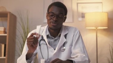 Sanal doktor. Web randevusu. Eczacılık ürünleri kozmetik ürünleri. Kendine güvenen erkek dermatolog, modern iç mekanda tüpte krem yazıyor..