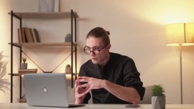 Digital marketing. Internet job. Professional communication technology. Confident intelligent business man working from home using laptop phone at modern workplace interior.
