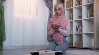 Kuran namaz kılıyor. Sadık Müslüman. İslam kültürü. Sakin odaklı kadın tesettürlü geleneksel giysiler içinde Ramazan 'da evde, oturma odasında yerde Kur' an okuyor..