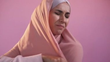Başörtüsü yasağı. Örtülü protesto. Kadın hakları için. Cinsiyet eşitliği. Pembe stüdyo arka planında, baş örtüsü takan sinirli bir kadın..