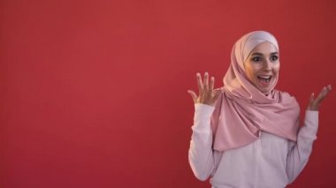 Wow expression. Shocked woman. Omg face. Unexpected surprise. Amazed excited expressive female in hijab isolated on red copy space advertising background.