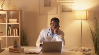 Sıkılmış doktor. Gece vardiyası. Profesyonel yorgunluk. Modern iş yerinde geç saatlere kadar kahve içerek sağlık hizmetlerini izleyen yorgun erkek sağlık çalışanı..