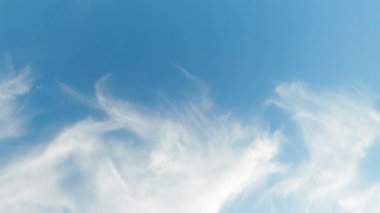 Clear sky. Dreamful freedom. Tranquil mood. Clean blue heaven with light plumy white clouds in sunny daylight flying through slow motion.