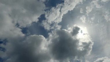 Sky magic. Weather changing. Aerial view. Thick gray white fluffy clouds flying away in blue cloudy heaven with sun rays fast motion.
