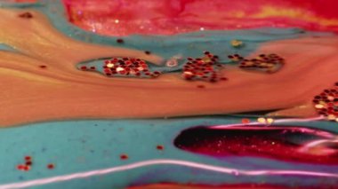 Abstract painting. Acrylic magic. Creative art. Peach pink fluid stream of paint floating and mixing together with glittered smoke blue in macro shooting.