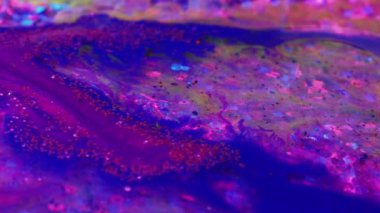 Creative art. Fluid magic. Painting process. Purple and blue glittered stream of liquid paint floating and mixing together in macro shooting.