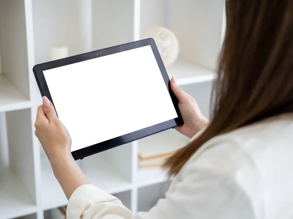 Video conference. Casual woman. Digital mockup. Unrecognizable lady holding tablet computer with blank screen in hands light room interior.