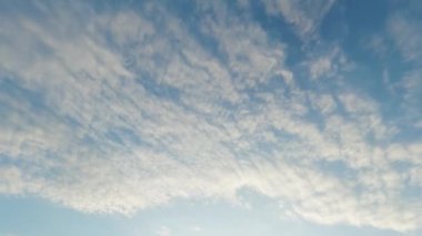 Daylight sky. Magic world. Atmosphere view. Clear light blue heaven with white fluffy sunset clouds flying away on day fast motion.