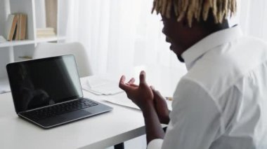 Successful work. Excited man. Virtual communication. Unrecognizable black happy guy sitting desk with opened laptop blank screen clapping hands in light room interior.