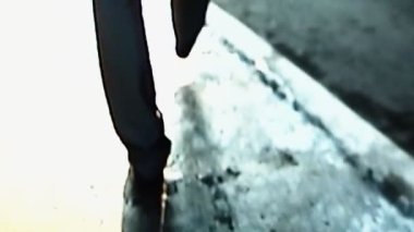 Glitched VHS video. City walk. Retro 90s. Defocused confident handsome man looking back winking on old grunge street with analog TV static noise flicker distortion effect.