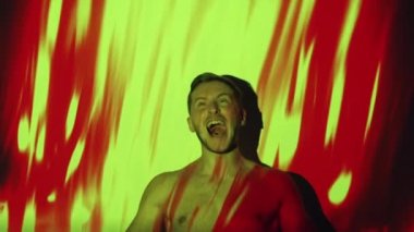 Evil man. Hell inferno. Angry devil. Horror nightmare. Silhouette of furious mad shirtless guy screaming burning in red yellow abstract hot fire flame projector light.