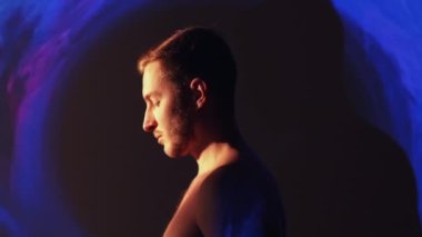Spiritual enlightenment. Yoga meditation. Mindfulness nirvana. Peaceful relaxed shirtless man in neon blue pink color aura mist cloud swirl projector light.