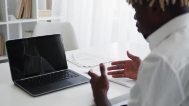 Great job. Supporting man. Virtual communication. Unrecognizable black guy sitting desk with opened laptop blank screen showing thumbs up in light room interior.
