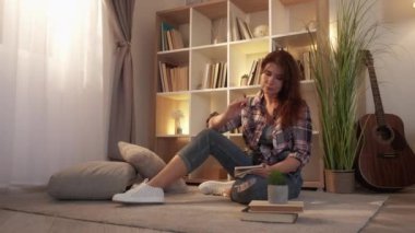 Muse inspiration. Romantic adult woman. Home leisure. Pretty casual lady sitting floor making notes in cozy atmosphere in light room interior.