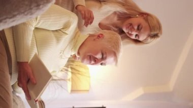 Happy Mothers Day. Womens holiday. Daughter love. Happy sincere female family exchanging gifts hugging at home living room vertical.