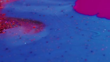 Fluid magic. Creative art. Abstract painting. Purple stream of liquid paint floating and mixing together with glittered blue creating leaf shape in macro shooting.